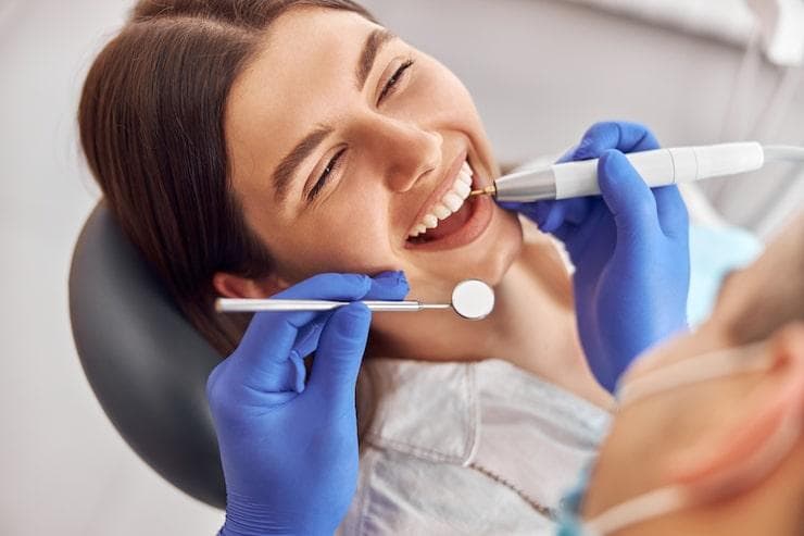 a woman getting her teeth examined happily by a dentist