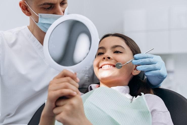 A girl getting her teeth examined by a dentist to maintain her oral health