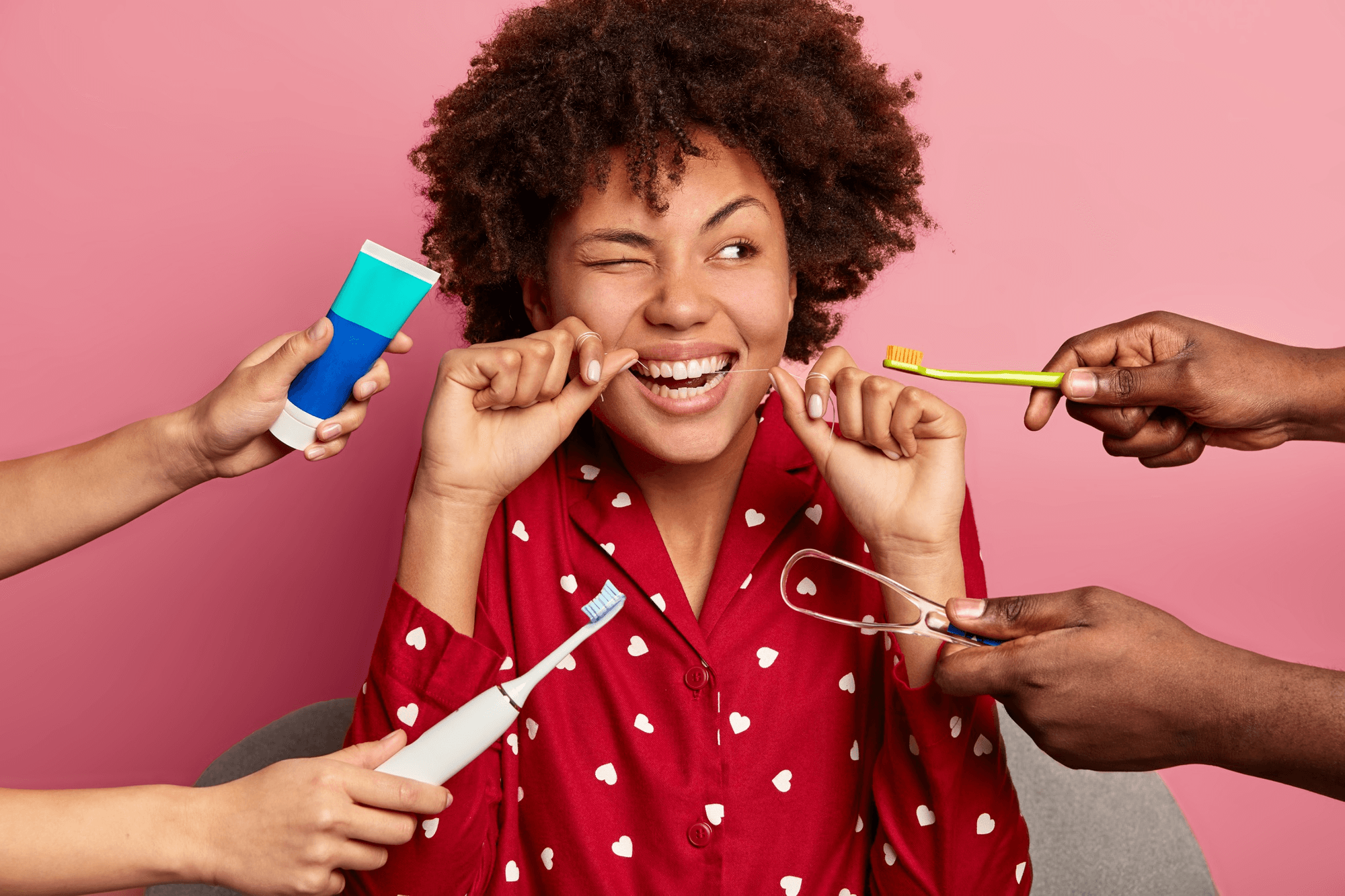 Woman with toothbrush, floss, and tongue scraper.