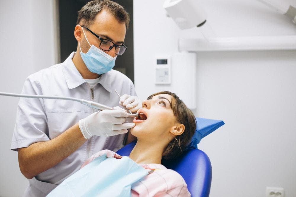 A dentist examines a young woman's teeth.