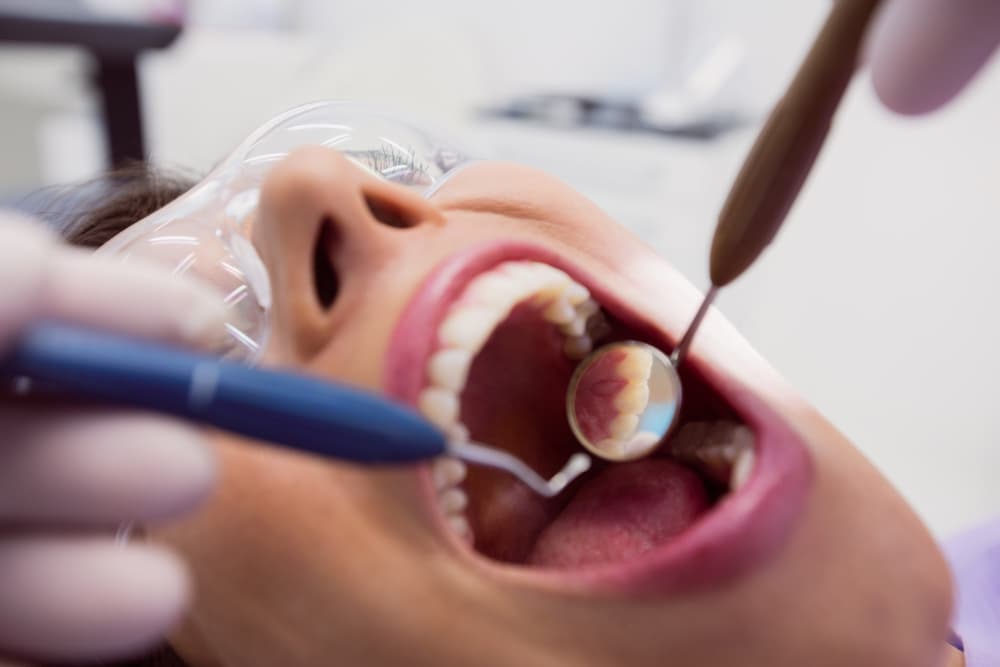 Dentist examining a female patient with tools.