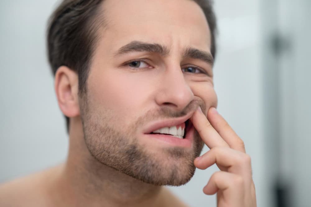 Man checking his teeth and looking disturbed.